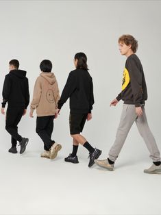 four young men are walking in the same direction, one is wearing a hoodie