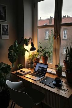 an open laptop computer sitting on top of a wooden desk in front of a window