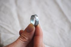 a person holding a piece of metal in their hand, with the ring on it's finger