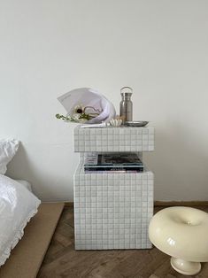 a bed room with a nightstand and a white chair next to it on top of a hard wood floor