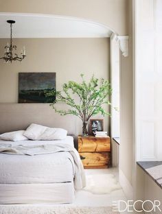 a bed with white sheets and pillows in a bedroom next to a painting on the wall