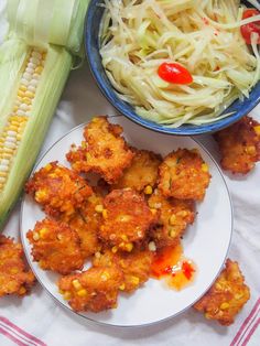 corn on the cob, coleslaw and other foods are sitting on plates