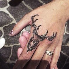 a person's hand with a deer head tattoo on it, and two fingers