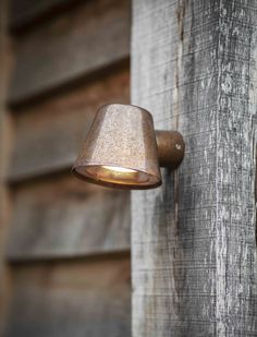 an old fashioned wall light on the side of a wooden building with weathered wood siding