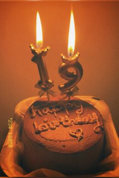 a birthday cake with two lit candles on top