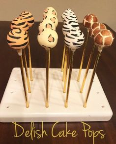 cake pops decorated with zebra and giraffe print on sticks are sitting on a white tray