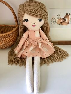 a stuffed doll sitting on top of a table next to a basket and wall hanging