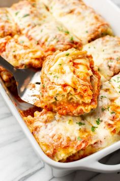 a casserole dish with meatballs and cheese being scooped from the casserole