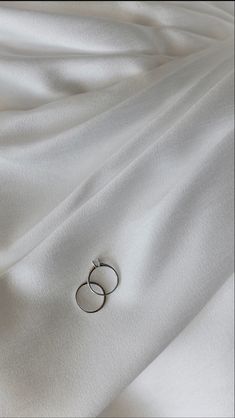 two silver rings sitting on top of a white sheet