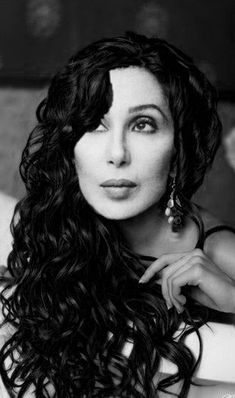 a black and white photo of a woman with long curly hair, wearing large earrings