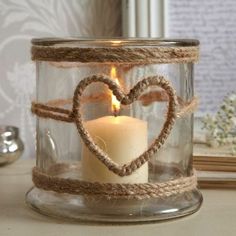 a candle in a glass jar with a heart on the front and rope around it