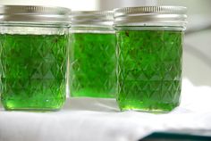 three jars filled with green liquid sitting on top of a table