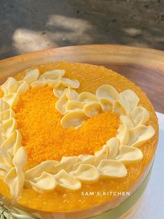 an orange cake with white icing on a wooden platter in the shape of a heart