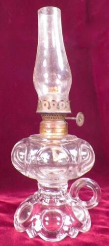 an old fashioned glass oil lamp sitting on a red cloth