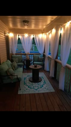 an outdoor living room with white curtains and lights on the ceiling, couches and coffee table