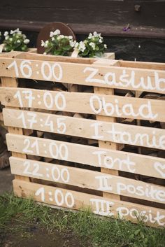 wooden pallets with white writing on them and some flowers in the middle one side