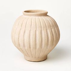 a white ceramic vase with wavy lines on the top and bottom, against a white background