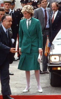 a woman in a green suit talking to a man