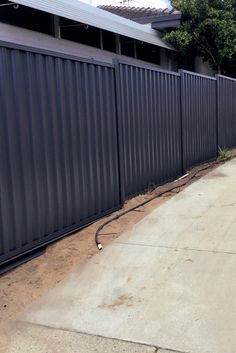 a fire hydrant sitting on the side of a road next to a metal fence