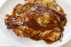 a white plate topped with meat covered in gravy and sauce on top of it