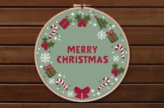 a cross stitch christmas ornament hanging on a wooden wall with the words merry christmas