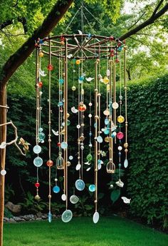 a wind chime hanging from a tree in the grass with lots of glass beads