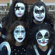 four people with their faces painted like clowns posing for a photo in front of a brick building