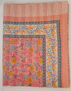 an old pink and yellow cloth with floral designs on the edges, sitting on a white surface