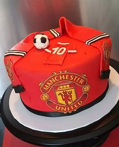 a cake that is shaped like a manchester united shirt and has a soccer ball on it