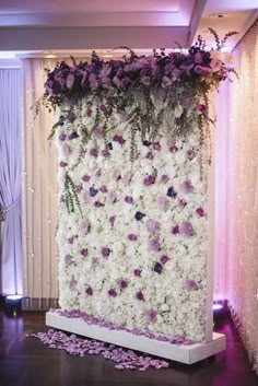 a white and purple backdrop with flowers on the wall for a wedding ceremony or reception