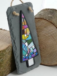 a small stained glass piece sitting on top of a tree stump next to some logs