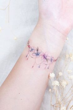 a woman's arm with flowers on it and the wrist is covered in pink ink