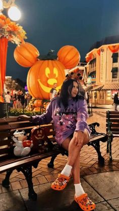 a woman sitting on top of a wooden bench in front of pumpkins and jack - o'lanterns