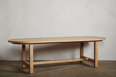 a wooden table sitting on top of a floor next to a white wall and cement floor