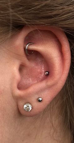 a woman's ear with three piercings on it