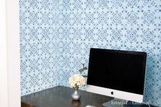 a desktop computer sitting on top of a wooden desk next to a vase with flowers