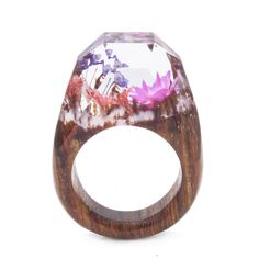 a wooden ring with flowers on it and a clear stone in the middle, against a white background