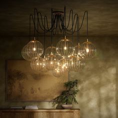 a large chandelier hanging from the ceiling over a table with a potted plant on it