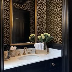 a bathroom with leopard print wallpaper and gold accents on the mirror above the sink