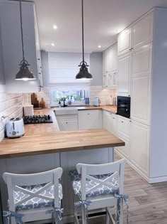 two chairs are sitting in front of the kitchen counter and island with stools on it