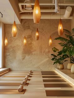 a room with several lights hanging from the ceiling and some plants in vases on the floor