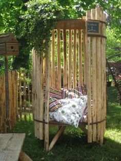 a chair made out of wooden sticks sitting on top of a lush green field next to a tree