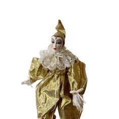 a gold and white clown doll standing in front of a white background