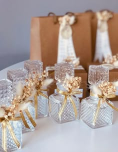 four clear glass vases with gold ribbons and flowers in them sitting on a table