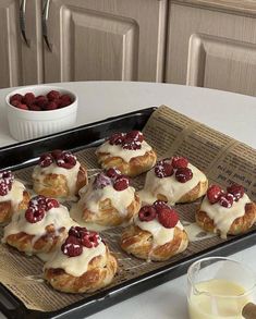 some croissants with cream and raspberries are on a tray