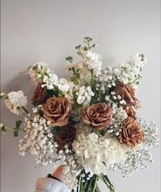 a vase filled with lots of white and brown flowers