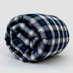 a blue and white checkered comforter on a grey background with the top rolled up