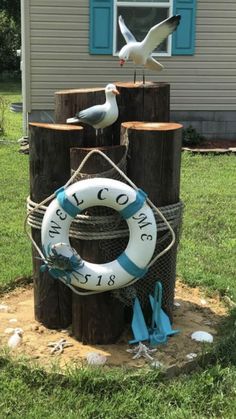 two seagulls sitting on top of wooden posts in front of a house with a life preserver