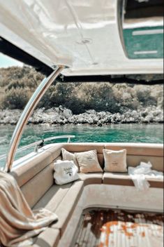 the inside of a boat with pillows on it's seat and water in the background