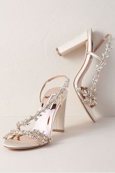 a pair of white high heeled shoes with crystal embellishments